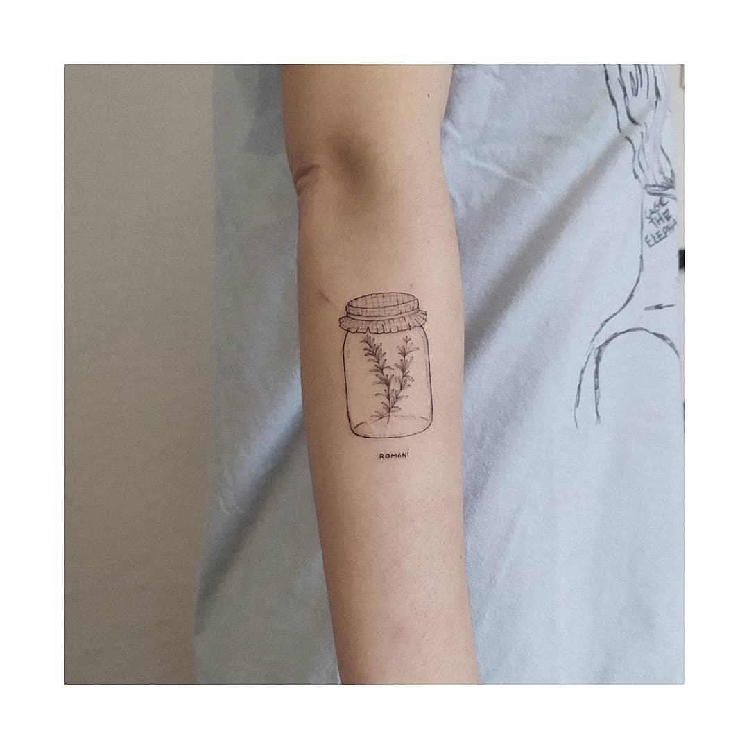 Tatuaje de línea fina: tarro de romero en el antebrazo